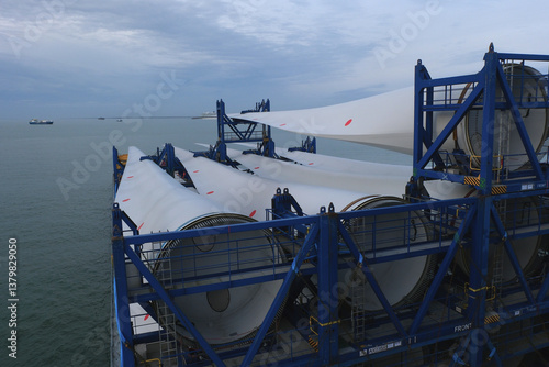 Long blades with root ends of wind turbine loaded and lashed on the heavy load carrier vessel.
