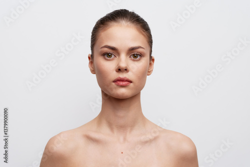 Obraz na płótnie Portrait of a young woman with natural makeup, neutral expression, and smooth skin against a plain white background Ideal for beauty and fashion related visuals w salonie