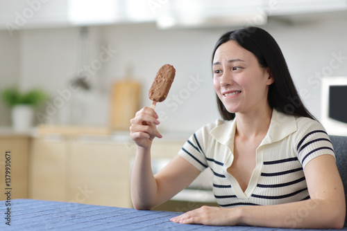 Asian woman looking at chocolate ice cream at home