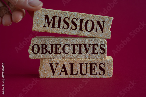 Obraz na płótnie Mission objectives values symbol. Concept words Mission Objectives Values on brick blocks. Beautiful red background. Businessman hand. Business mission objectives values concept. w salonie