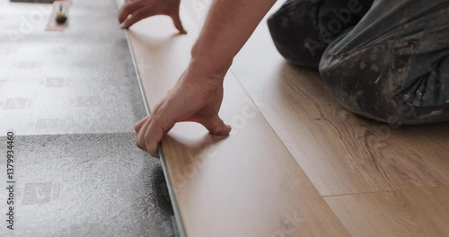 Worker, lays laminate on a black backing. Technology and process. Repair of the floor of the house.