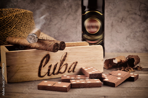 Cigar with smoke, tobacco leaf.  Handmade in Cuba. Still life with domino play.