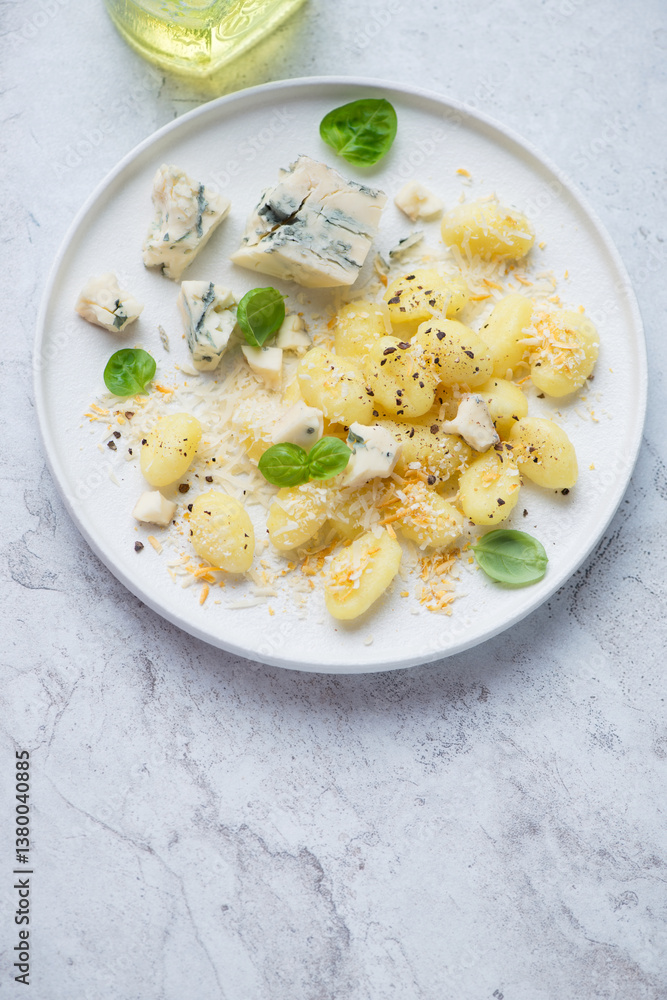 Plate of italian potato gnocchi served with blue cheese, vertical shot on a white stone background with space, elevated view Plate of italian potato gnocchi served with blue cheese, vertical shot on a white stone background with space, elevated view
