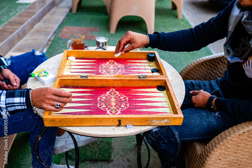 Close up[ view of two persons playing backgammon on a terrace