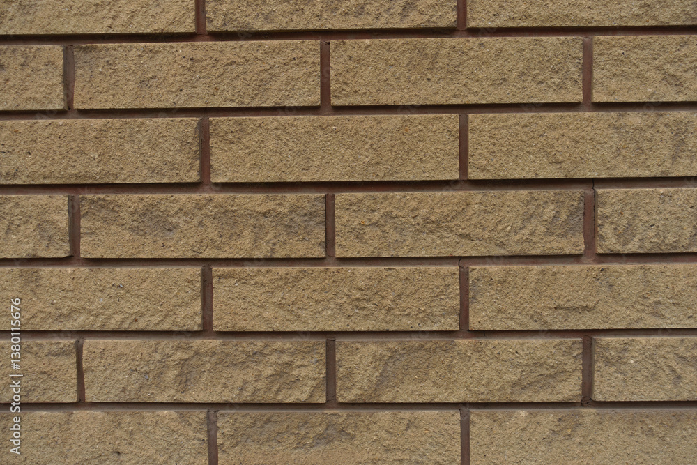 Close shot of beige split face brick veneer wall with running bond layout
