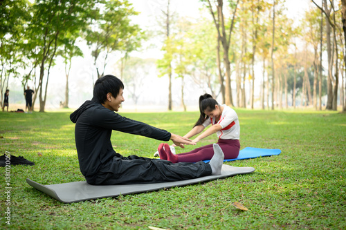 Young man and woman stretching together on yoga mats in a green park. Healthy lifestyle concept
