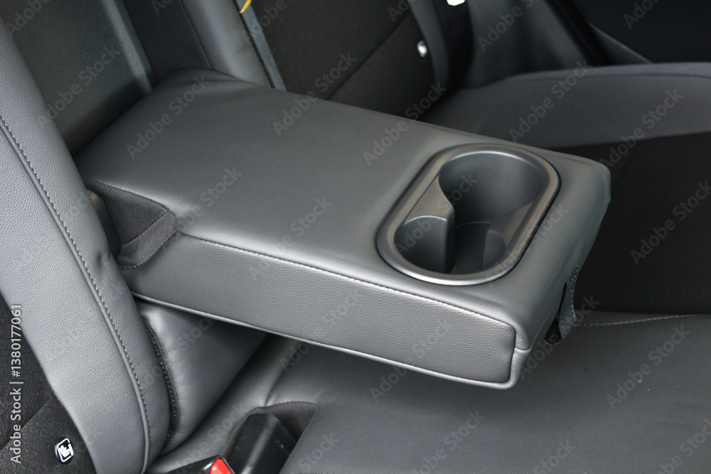 Fototapeta premium Leather trimmed anfolding armrest with cup holders in rear seats inside a vehicle. Electric car interior. Clean leather interior.