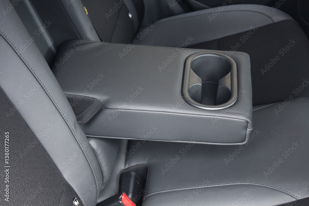 Leather trimmed anfolding armrest with cup holders in rear seats inside a vehicle. Electric car interior. Clean leather interior. Leather trimmed anfolding armrest with cup holders in rear seats inside a vehicle. Electric car interior. Clean leather interior.
