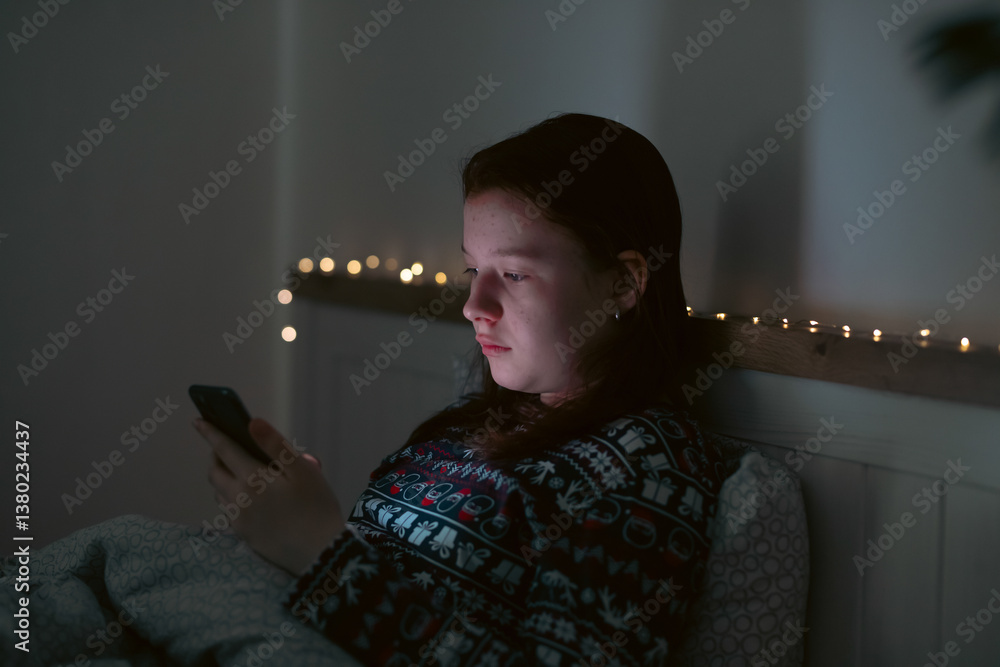 Girl using smart phone while lying on bed in bedroom