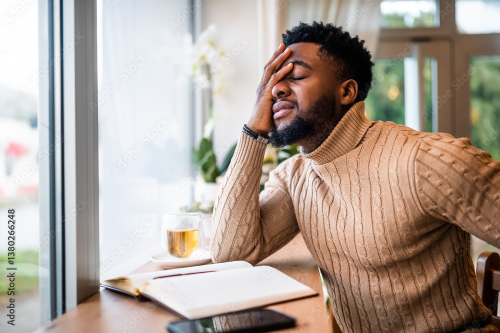 Young black man sitting in bar. He is using smartphone and notepad. Freelancer making business plans. Young black man sitting in bar. He is using smartphone and notepad. Freelancer making business plans.