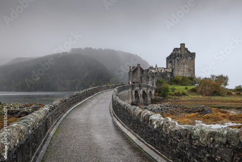 Obraz na płótnie Eilean Donan Castle stands majestically amid autumn hues, its reflection shimmering in calm waters. Misty Highlands and golden trees create a scene of timeless beauty. w salonie