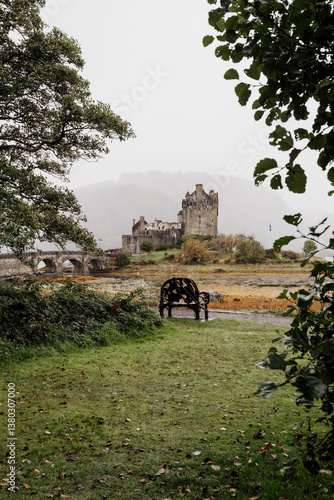 Obraz na płótnie Eilean Donan Castle stands majestically amid autumn hues, its reflection shimmering in calm waters. Misty Highlands and golden trees create a scene of timeless beauty. w salonie