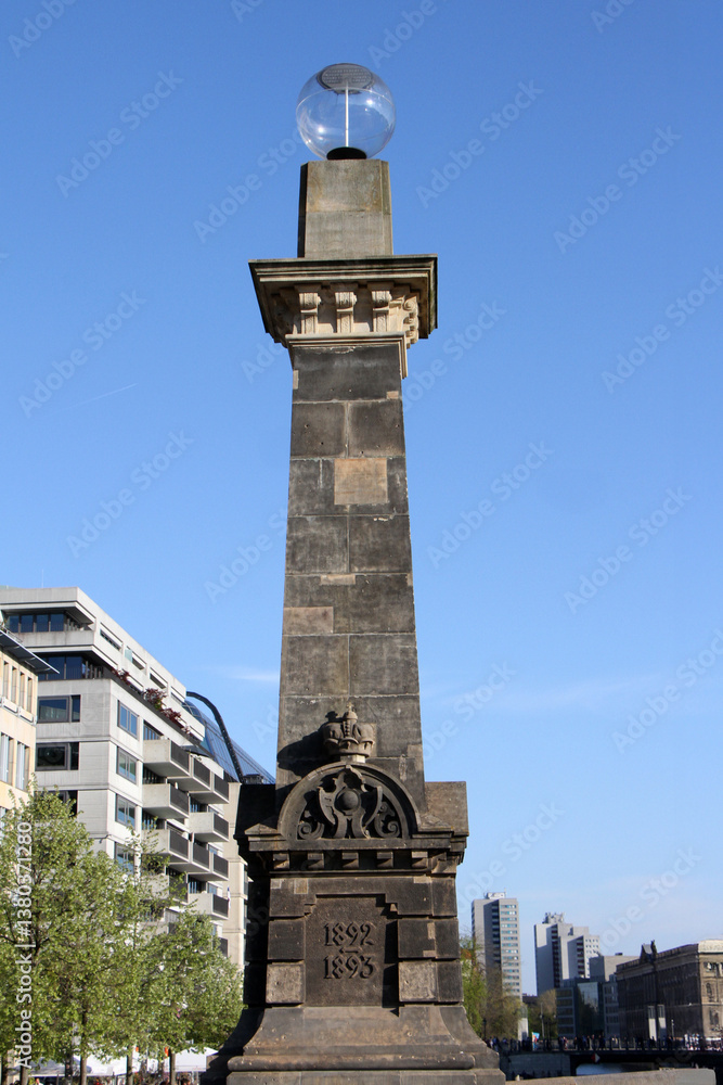Obraz premium Historic Obelisk Monument on Friedrichsbrücke in Berlin with Modern Buildings in Background