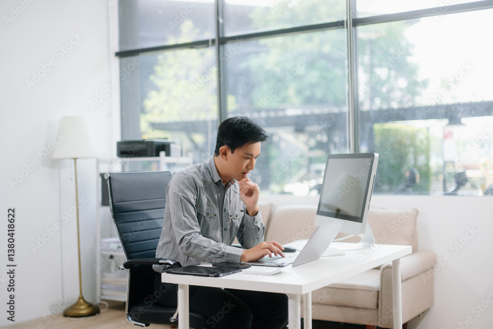 Confident businessman working on finance analysis with a tablet and laptop at office desk. Confident businessman working on finance analysis with a tablet and laptop at office desk.