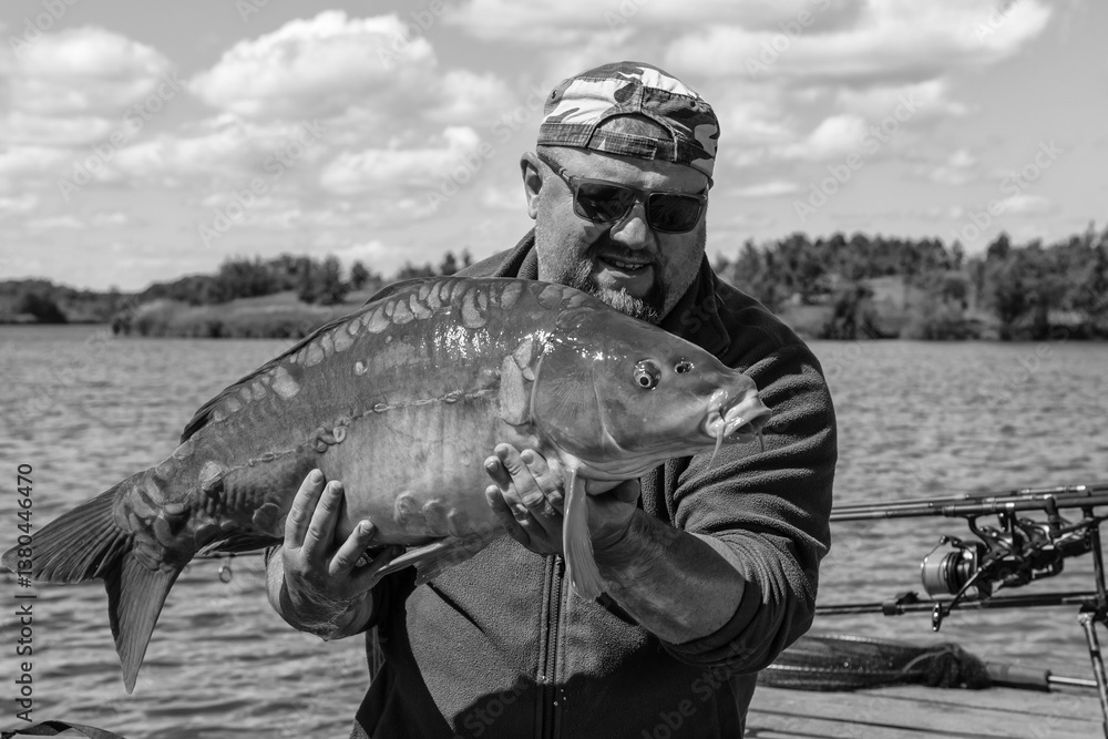 Carpfishing session at the Lake.lucky fisherman holding a giant common carp.Angler with a big carp fishing trophy.Fishing adventures.Fish trophy Carpfishing session at the Lake.lucky fisherman holding a giant common carp.Angler with a big carp fishing trophy.Fishing adventures.Fish trophy