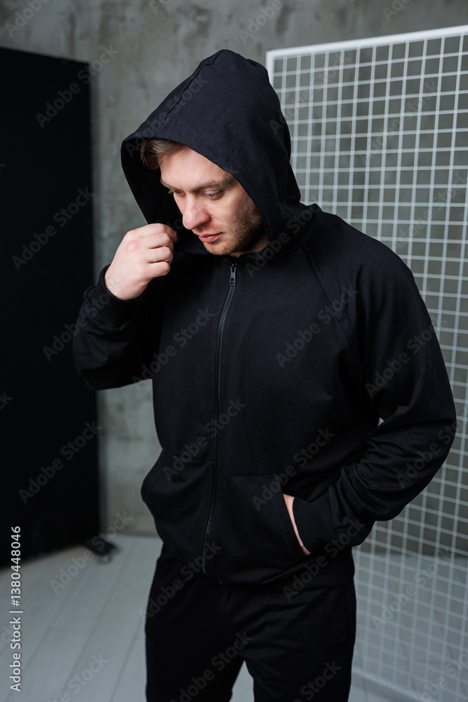 A Stylish Man Dressed in a Black Hoodie is Posing Confidently in an Urban Setting This Scene Serves as Modern Fashion and Lifestyle Inspiration for Those Looking to Elevate Their Style