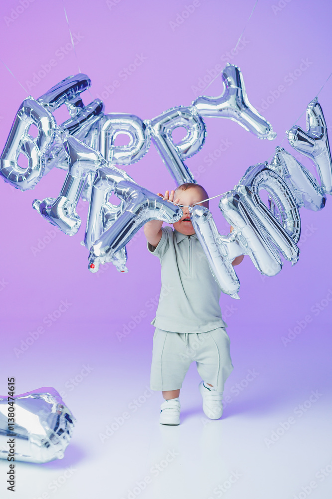 A Joyful Celebration An adorable toddler is joyfully holding onto some colorful Happy Birthday balloons, set against a vibrant purple background, capturing the essence of innocence and fun