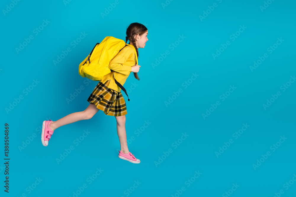 Joyful schoolgirl with yellow backpack running against blue background, symbolizing energy and excitement for school and learning Joyful schoolgirl with yellow backpack running against blue background, symbolizing energy and excitement for school and learning