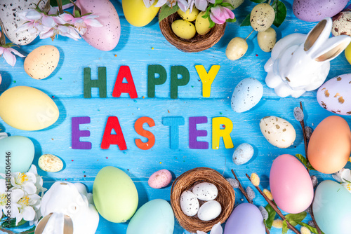 Spring Easter holiday top view flat lay background with eggs, bunny rabbits and spring flowers. Bright colorful greeting card background with copy space.