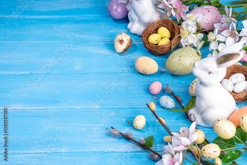 Spring Easter holiday top view flat lay background with eggs, bunny rabbits and spring flowers. Bright colorful greeting card background with copy space.