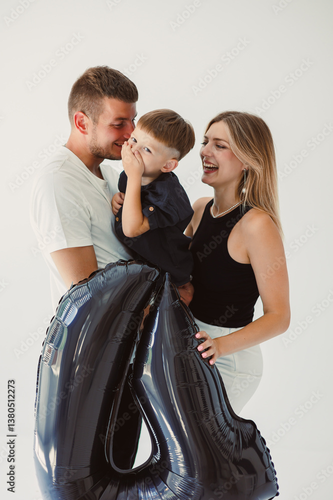 In a heartwarming family moment, parents are joyfully celebrating together with their child, who is holding a colorful balloon, creating a beautiful atmosphere filled with love and happiness