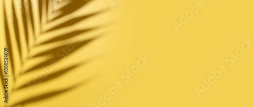Sun shadow from tropical palm leaves on yellow background. Abstract summer background, trendy wallpaper for design, advertising. Beach vacation and travel concept