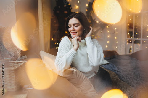 Obraz na płótnie Cute girl in New Year's locations in a cozy living room. Woman at home for the new year. w salonie