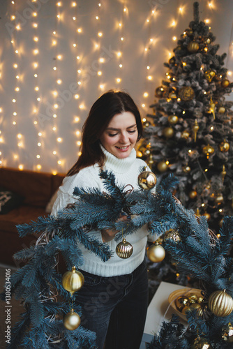 Obraz na płótnie Cute girl in New Year's locations in a cozy living room. Woman at home for the new year. w salonie