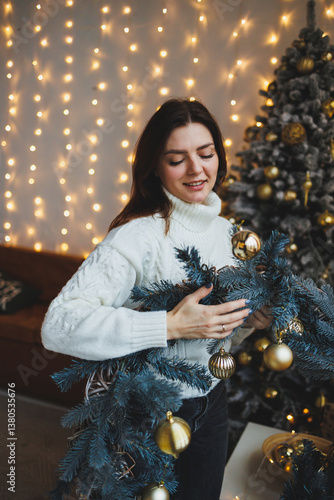 Obraz na płótnie Cute girl in New Year's locations in a cozy living room. Woman at home for the new year. w salonie
