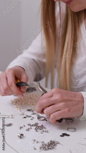Small Business.  A jewelry designer carefully crafting handmade accessories using beads, pliers, and metal parts. Close-up of hands creating elegant jewelry pieces