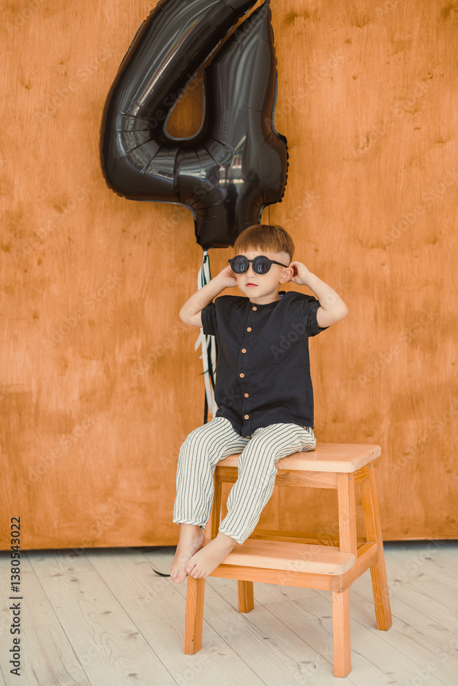 A Stylish Young Boy is Celebrating His 4th Birthday with Exciting Fun Sunglasses and a Trendy Outfit, making the event a memorable occasion filled with happiness and colorful cheerfulness