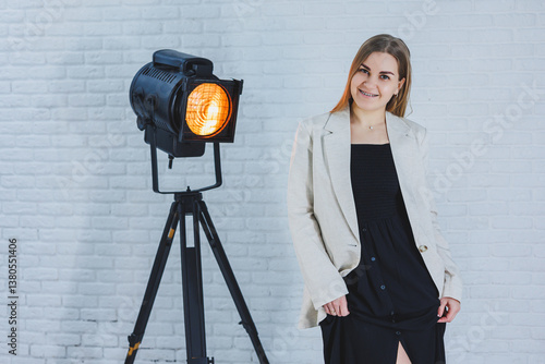A young woman is posing elegantly in front of a sophisticated studio lighting setup, specially arranged for a stylish and creative fashion shoot that accentuates modern beauty and grace