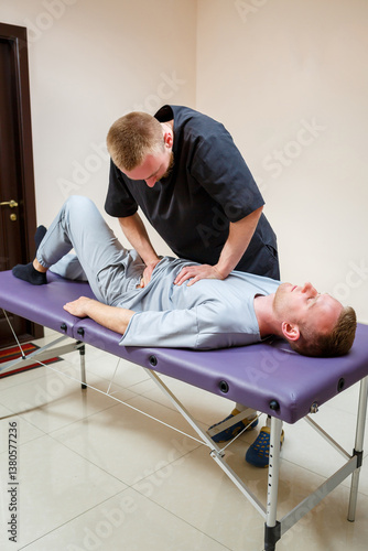 Obraz na płótnie In a dedicated professional physical therapy session, an expert chiropractor skillfully treats a male patient experiencing back pain, aiming to provide effective relief and improve overall wellness w salonie