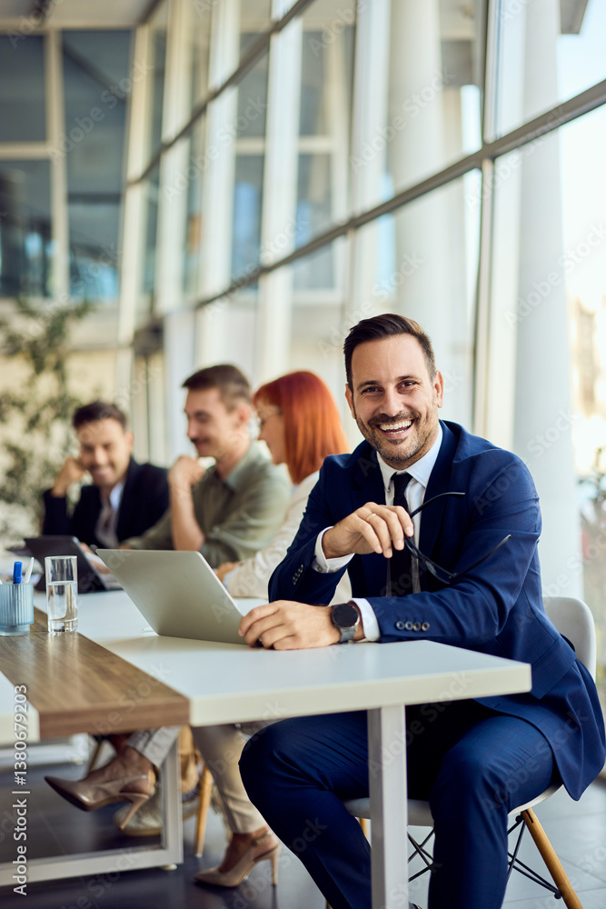 Smiling Businessman in Conference Room During Casual Office Meeting with Team