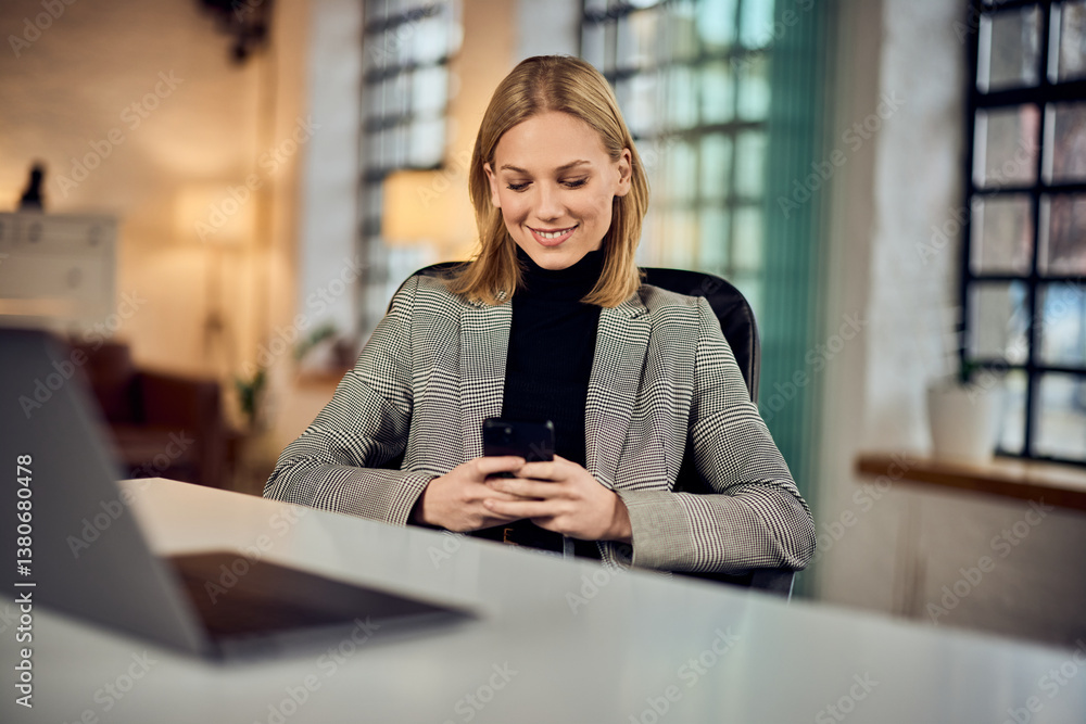 Smiling Businesswoman Using Smartphone at Office Desk During Work Time Smiling Businesswoman Using Smartphone at Office Desk During Work Time