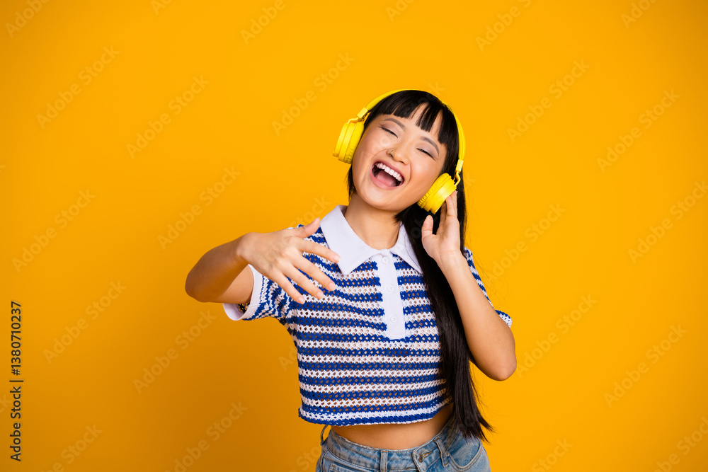 Smiling Young Woman in a Casual Striped Top Enjoying Music with Yellow Headphones in a Vibrant Studio Setting Smiling Young Woman in a Casual Striped Top Enjoying Music with Yellow Headphones in a Vibrant Studio Setting