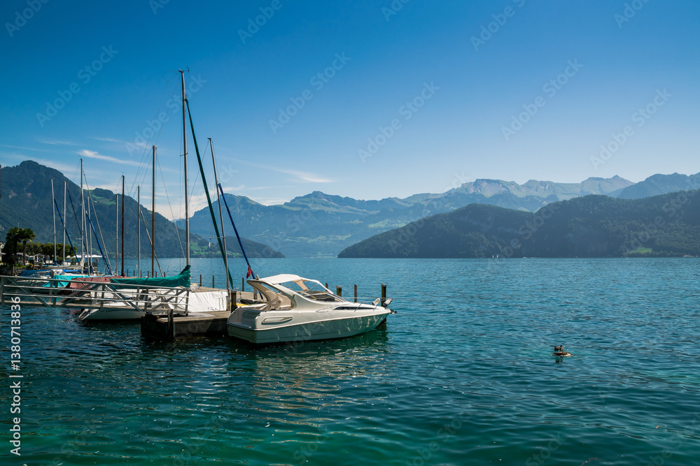 Sailing boats with jetty at lake lucerne on a sunshiny summers day. Mountains and forest in the background. Reflection of the water. Beautiful and serene atmosphere. Sailing boats with jetty at lake lucerne on a sunshiny summers day. Mountains and forest in the background. Reflection of the water. Beautiful and serene atmosphere.