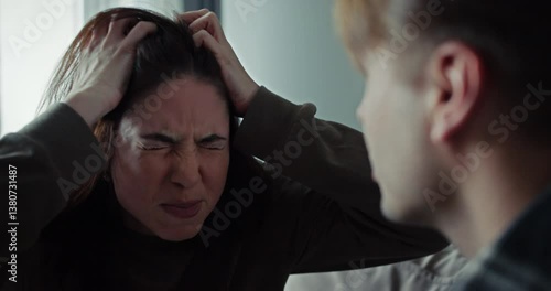Over the shoulder brunette girl gets angry and yells at her boyfriend during an argument on the sofa at home