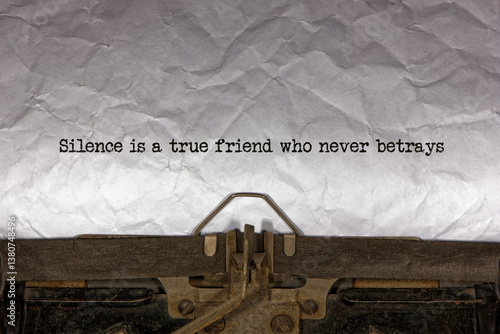 silence is a true friend who never betrays close up of a phrase being typed and centered on a sheet of paper on an old vintage mechanical typewriter.