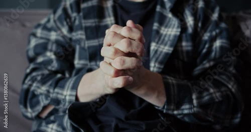 Close up a man in a plaid shirt restrains his strength and aggression and clenches his hand