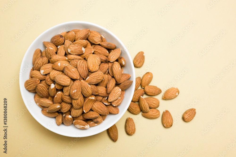 Top view of almonds into bowl on yellow background. Top view of almonds into bowl on yellow background.