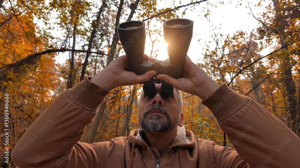 Amateur birdwatcher observing birds and other animals in nature with binoculars.