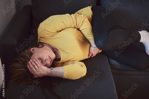 Woman with strong stomach ache, menstrual and digestive issues at home.