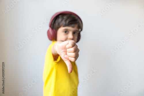 Cute little boy show thumb down gesture, close up. Say no, whims, emotions and facial expression. Dislike gesture