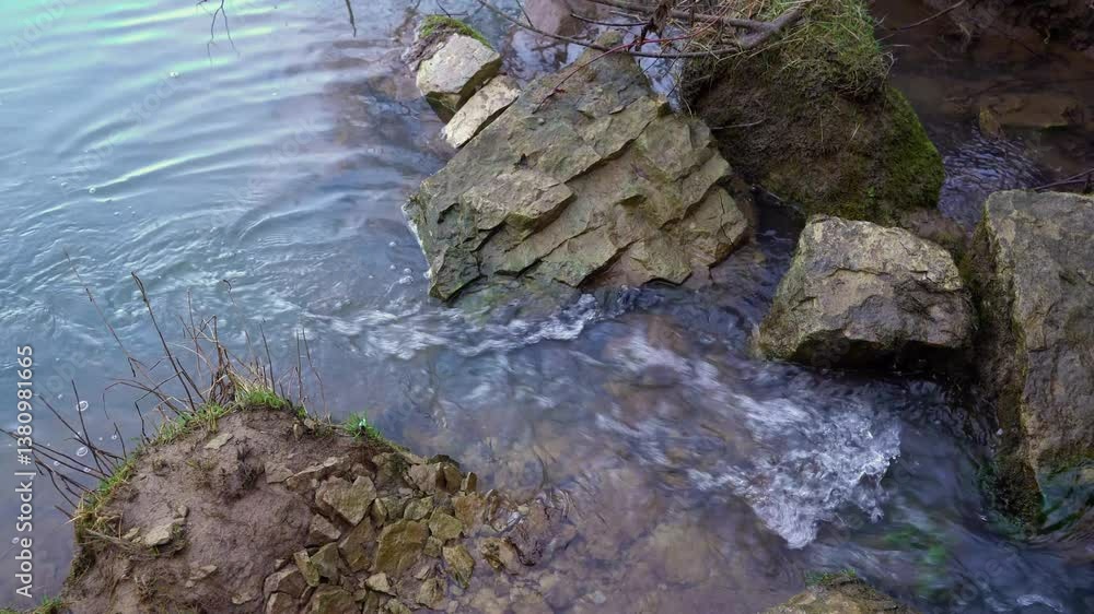 Gentle, clear water cascades over smooth stones found in a serene natural environment, beautifully showcasing the mesmerizing flow of water and the picturesque rocky shoreline all around Gentle, clear water cascades over smooth stones found in a serene natural environment, beautifully showcasing the mesmerizing flow of water and the picturesque rocky shoreline all around