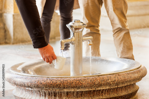 Fototapete Mann füllt warmes Heilwasser aus einem historischen Thermalbrunnen zur gesundhei