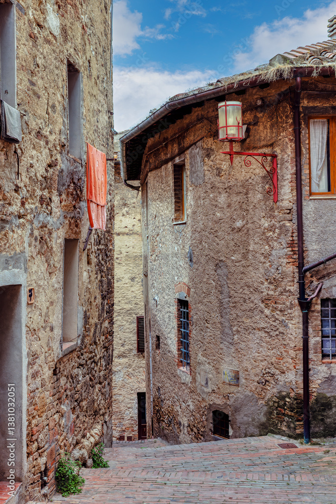 The narrow streets of San Gimignano, where rustic buildings with weathered stone facades stand. Picturesque Tuscan town. San Gimignano, Tuscany, Italy.
