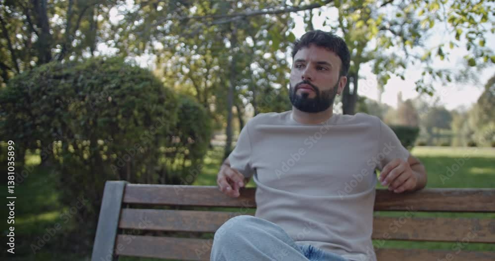 A young man sits on a park bench, experiencing a range of emotions from contemplative to content. A young man sits on a park bench, experiencing a range of emotions from contemplative to content.