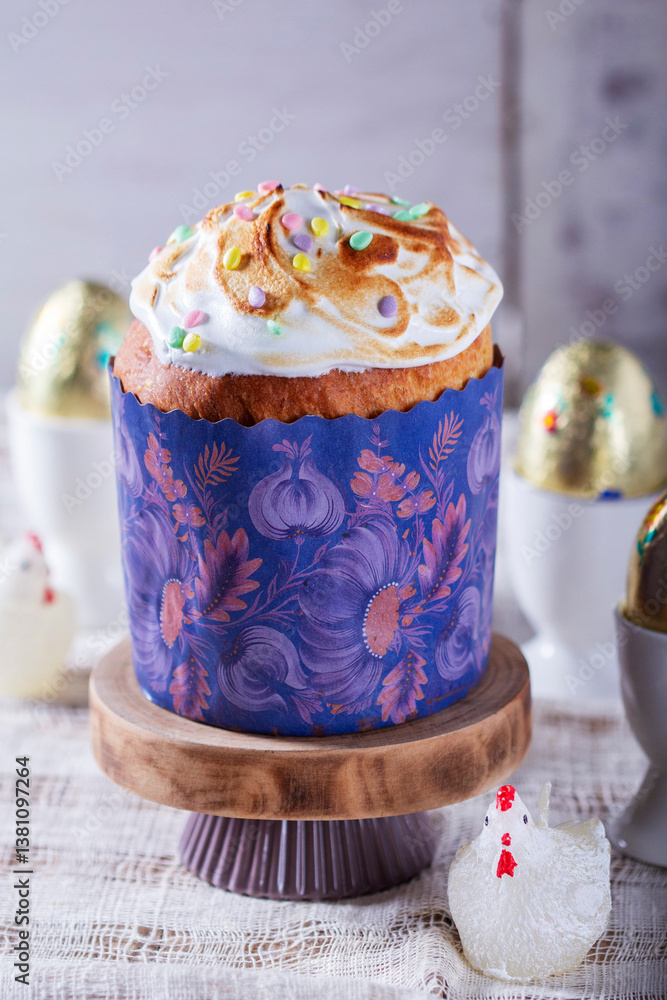 Easter cake, chocolate eggs in gold foil and chicken-shaped candles on a light background.