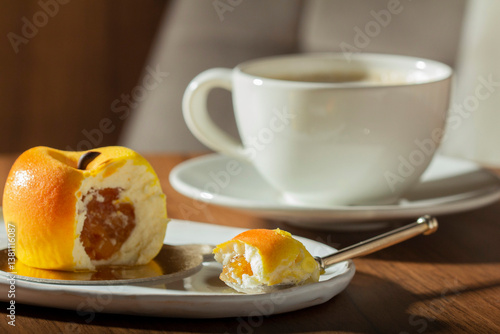 Obraz na płótnie Mousse cake with peach filling covered with velvet glaze and a cup of latte on a table in a cafe. w salonie